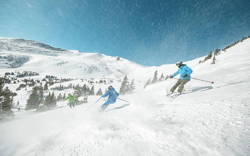 Skiers descending fresh powder slopes in Breckenridge, highlighting winter sports access from Breckenridge luxury rentals. Skiers descending fresh powder slopes in Breckenridge, highlighting winter sports access from Breckenridge luxury rentals.
