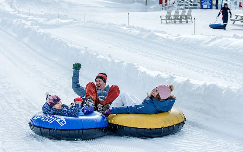 Children snow tubing in Big Sky, illustrating family-friendly activities offered through Big Sky luxury rentals. Children snow tubing in Big Sky, illustrating family-friendly activities offered through Big Sky luxury rentals.