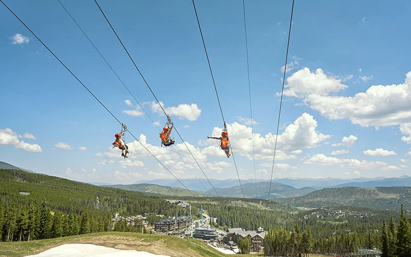 Ziplining over alpine forest with panoramic mountain views, showcasing outdoor activities near Breckenridge luxury rentals. Ziplining over alpine forest with panoramic mountain views, showcasing outdoor activities near Breckenridge luxury rentals.