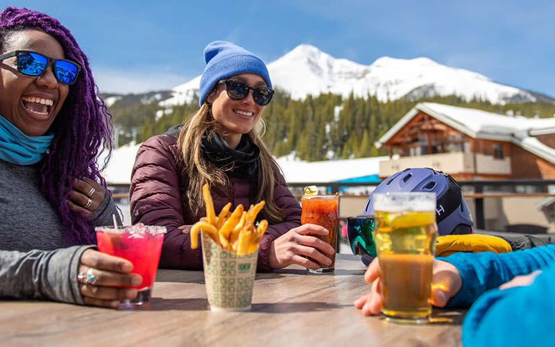 Guests enjoying après-ski drinks with mountain views, highlighting culinary experiences near Big Sky luxury rentals. Guests enjoying après-ski drinks with mountain views, highlighting culinary experiences near Big Sky luxury rentals.
