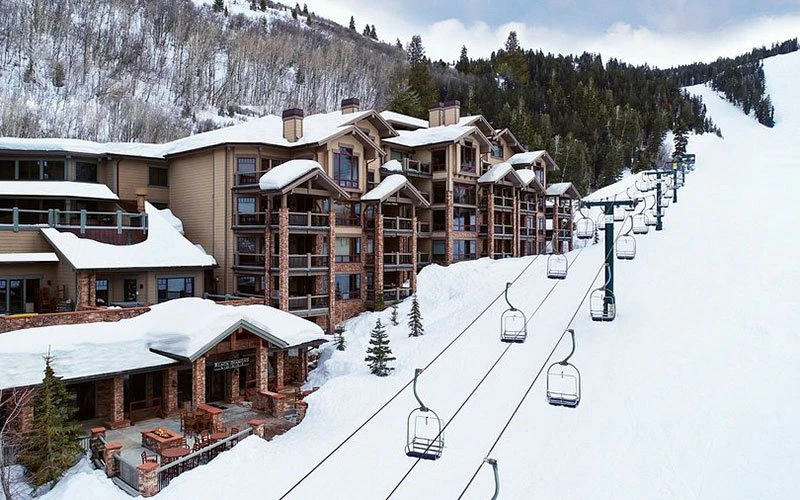 Exterior of Black Diamond Lodge directly beside the ski lift, emphasising slope-side Deer Valley ski-in/ski-out access and convenience.
