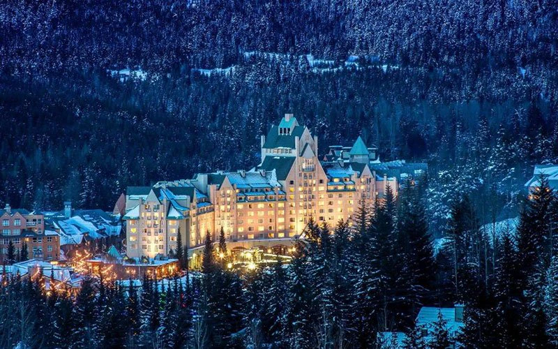 Fairmont Chateau Whistler ski-in/ski-out luxury hotel illuminated at night with mountain backdrop.