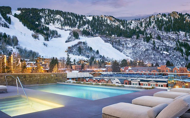 Rooftop pool and mountain backdrop at The Little Nell, a five-star Aspen ski-in/ski-out hotel with luxury services.
