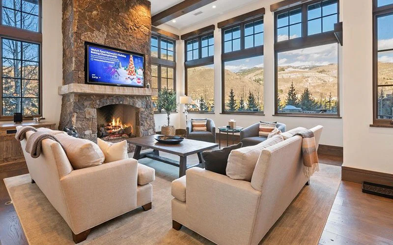 Alpenzauber Lodge Vail ski-in/ski-out home with spacious living room, stone fireplace, and Gore Range views.