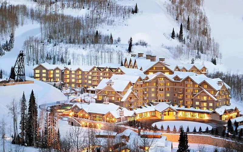 Exterior winter view of Montage Deer Valley resort surrounded by snow-covered trees, representing luxury Deer Valley Condos in Empire Pass.