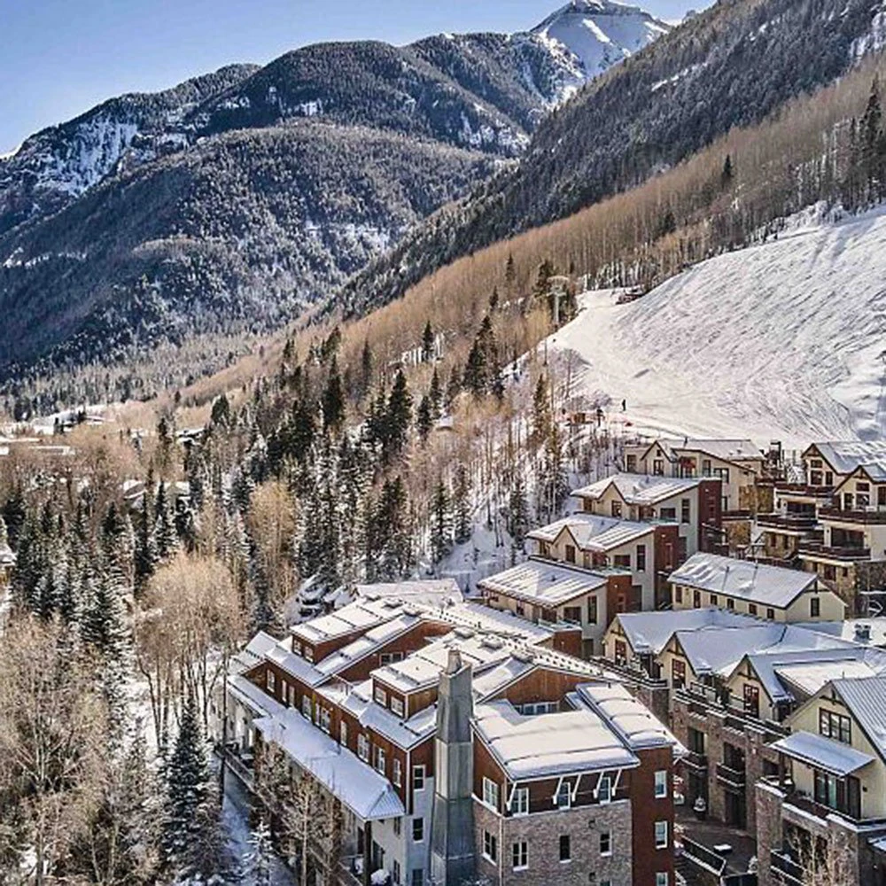 Aerial view of Element 52 Telluride condos nestled in the trees with ski slopes and mountain peaks in the background.