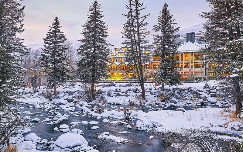 Snow-covered riverfront view of Grand Hyatt Cascade Village, one of the premium Vail Condos offering direct ski access and upscale amenities.