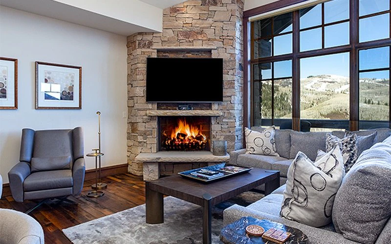 Interior living room of Arrowleaf Lodge with a stone fireplace and mountain views, showcasing upscale Deer Valley Condos in Empire Pass.