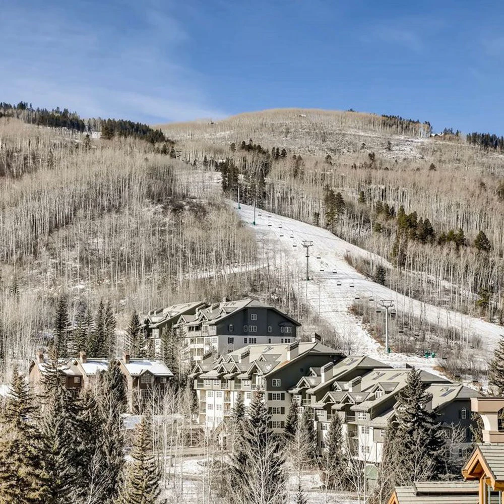 Scenic view of Beaver Creek condos nestled beneath ski slopes, with forested surroundings and direct access to mountain lifts – showcasing the convenience and charm of Beaver Creek condo rentals.