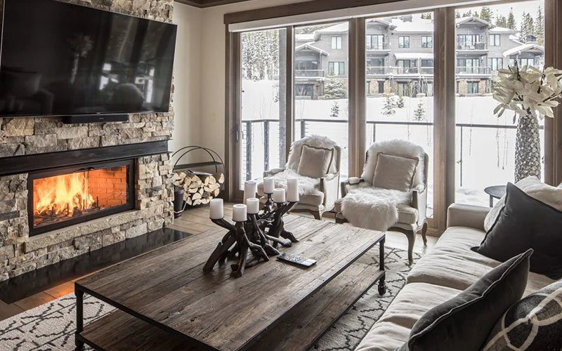 Cozy mountain-style living room at Wildwood, one of the private and refined Big Sky Condos with stone fireplace and forest views.