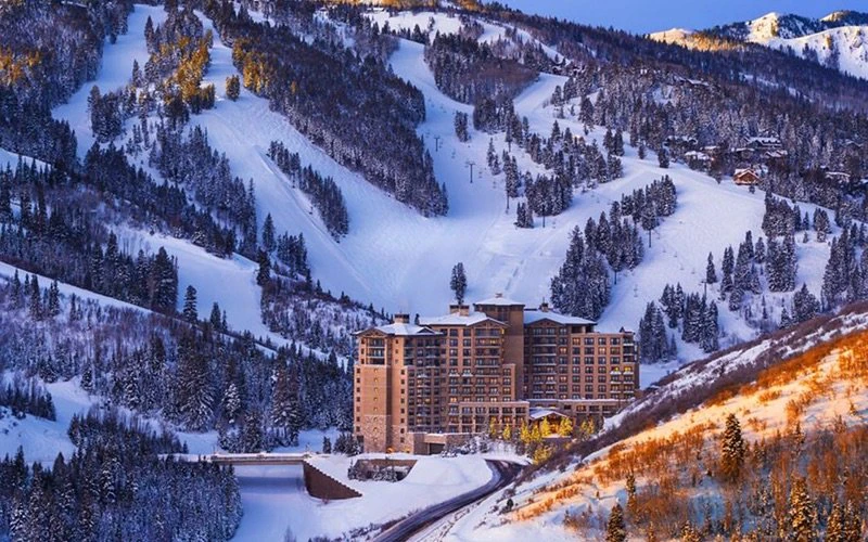 Snow-covered exterior of the St Regis with mountain backdrop, capturing dramatic and luxurious Deer Valley Condos in Snow Park.