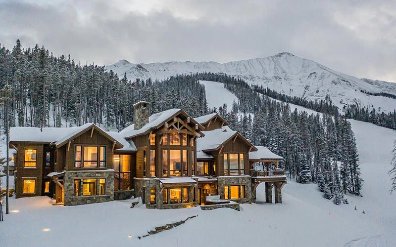 Elegant ski-in/ski-out Big Sky Condos at Lake Lodge, framed by snow-covered pines and Lone Mountain slopes in the background.