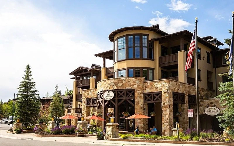 Exterior of The Chateaux in Silver Lake Village with flags and alpine architecture, highlighting elegant Deer Valley Condos with hotel-style amenities.