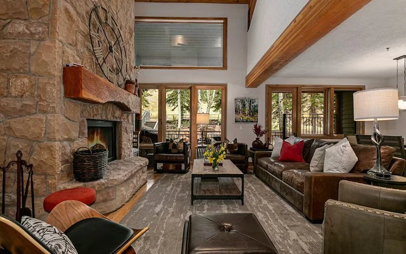 Rustic living room interior of Sterling Lodge with fireplace and leather sofas, showing spacious Deer Valley Condos with ski-in/ski-out access.