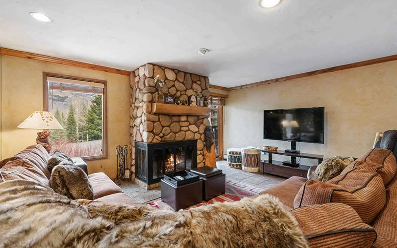 Living room with stone fireplace and plush seating at The Fallridge, one of the featured Vail Condos overlooking Golden Peak.