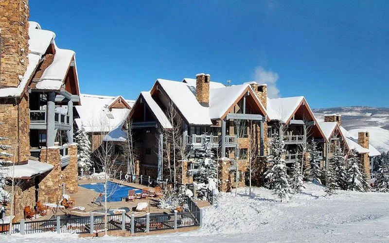 Snow-covered luxury Beaver Creek condo exterior at Bear Paw Lodge in Bachelor Gulch, showcasing rustic stone architecture and ski-in/ski-out convenience.