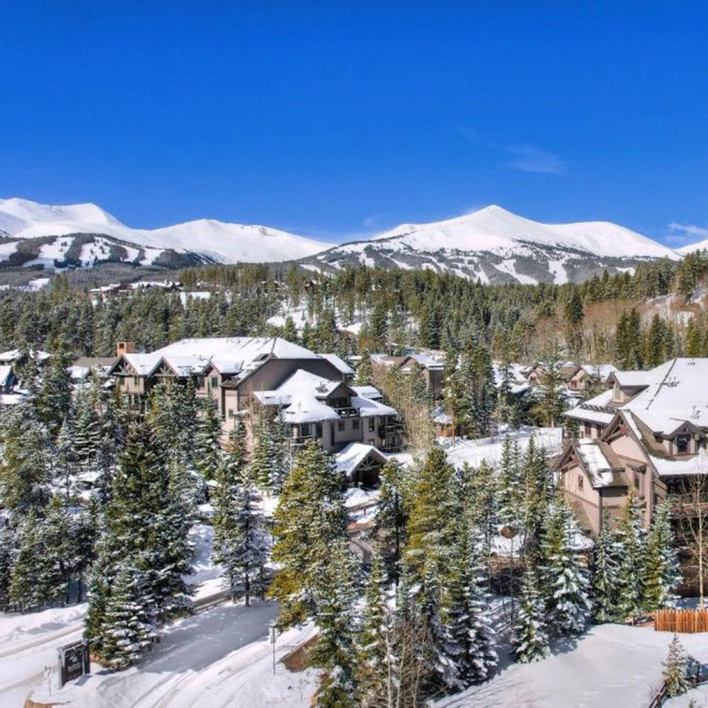 breckenridge-condos-intro-image-Mountain-Thunder-Lodge Winter landscape with luxury Breckenridge Condos nestled in the forest, offering views of snow-covered peaks and ski terrain