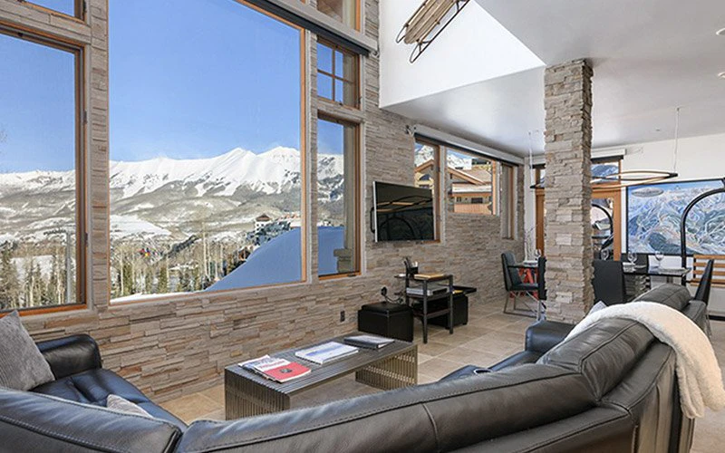 The Granita Telluride Vacation Rentals spacious living area with floor-to-ceiling windows and panoramic snowy mountain views.