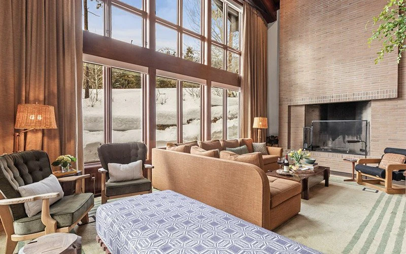 Big Trail Jackson Hole Vacation Rentals spacious living room with tall windows, cozy seating, and mountain views in Teton Village.